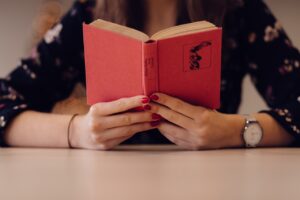 Dame læser i en rød bog med et flot ur på